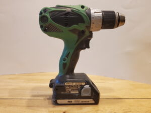 Hitachi Drill with 18 volt Lithium Battery on a wooden table with white backdrop